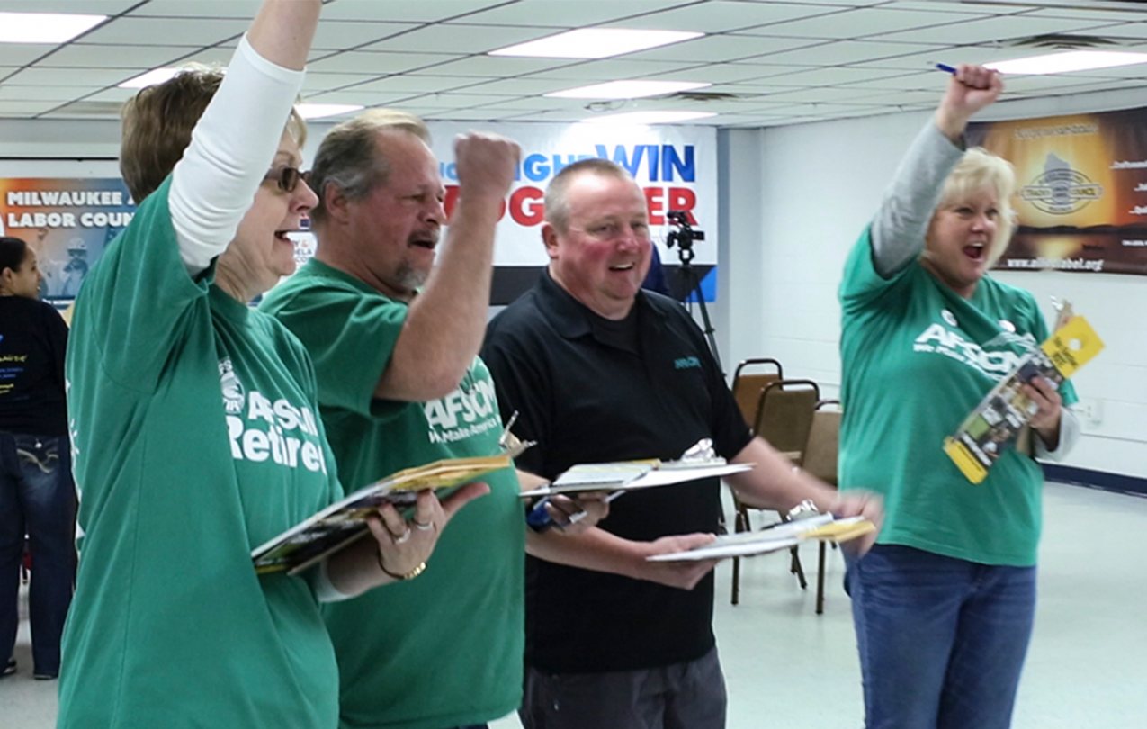 Photograph of two women and two men cheering - presumably for their winning candidate - and all of whom are wearing AFSCME shirts.